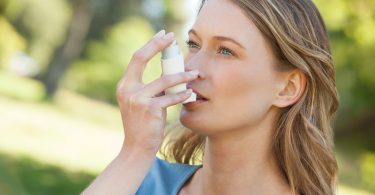 Foto einer jungen Frau, die einen Asthma-Inhalator verwendet