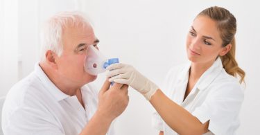 Foto eines COPD Patientenm der bei einer Reha den Umgang mit einer Sauerstoffmaske lernt