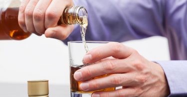 Foto eines Mannes mit Alkoholsucht, der sich Alkohol eingießt