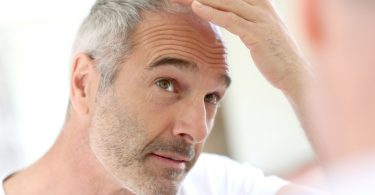 Foto: Mann kontrolliert seinen Haarausfall im Spiegel