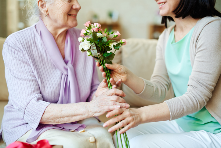 Foto einer Tochter, die ihrer Mutter Blumen in die Klinik bringt