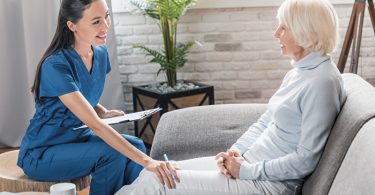 Pflegerin spricht mit Seniorin im Haus