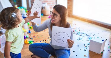Psychologin und Kleinkind bei der Therapie mit Emoji-Emotionen im Kindergarten