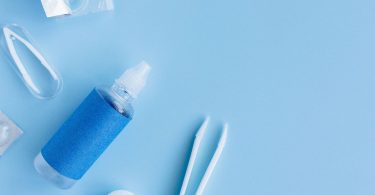 Pflegemittel für Kontaktlinsen mit Behälter und Pinzette auf blauem Grund