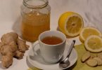 Tasse Tee mit Ingwerwurzel, Zitronenscheiben und einem Glas Honig