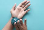 Hände rollen einen Igelball über das Handgelenk vor blauem Hintergrund