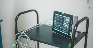 Monitor zur Überwachung von Puls und Sauerstoffsättigung auf einem Rollwagen im Krankenzimmer