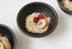 Schalen mit Haferbrei, Banane, Himbeeren und Chiasamen