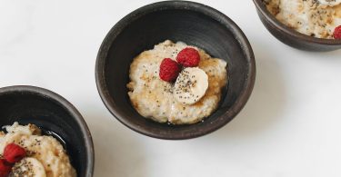 Schalen mit Haferbrei, Banane, Himbeeren und Chiasamen