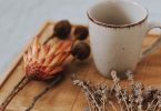 Keramikbecher auf einem Holztablett mit getrockneten Blumen und Lavendel