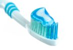 Zahnbürste mit blauer Zahnpasta vor weißem Hintergrund