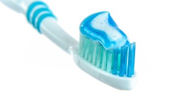 Zahnbürste mit blauer Zahnpasta vor weißem Hintergrund