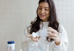 Junge Frau schüttet Kapseln eines Nahrungsergänzungsmittels aus einer Dose in ihre Hand