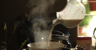 Dampfende Milch wird aus einer Kanne in eine Schale gegossen