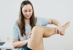 Physiotherapeutin bewegt das angewinkelte Bein eines Patienten im Knie