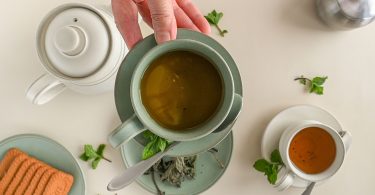 Teekannen und Tassen mit Kräutertee, Minze und Gebäck, von oben gesehen