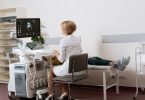 Ärztin an einem Ultraschallgerät, daneben liegt eine Patientin auf der Untersuchungsliege